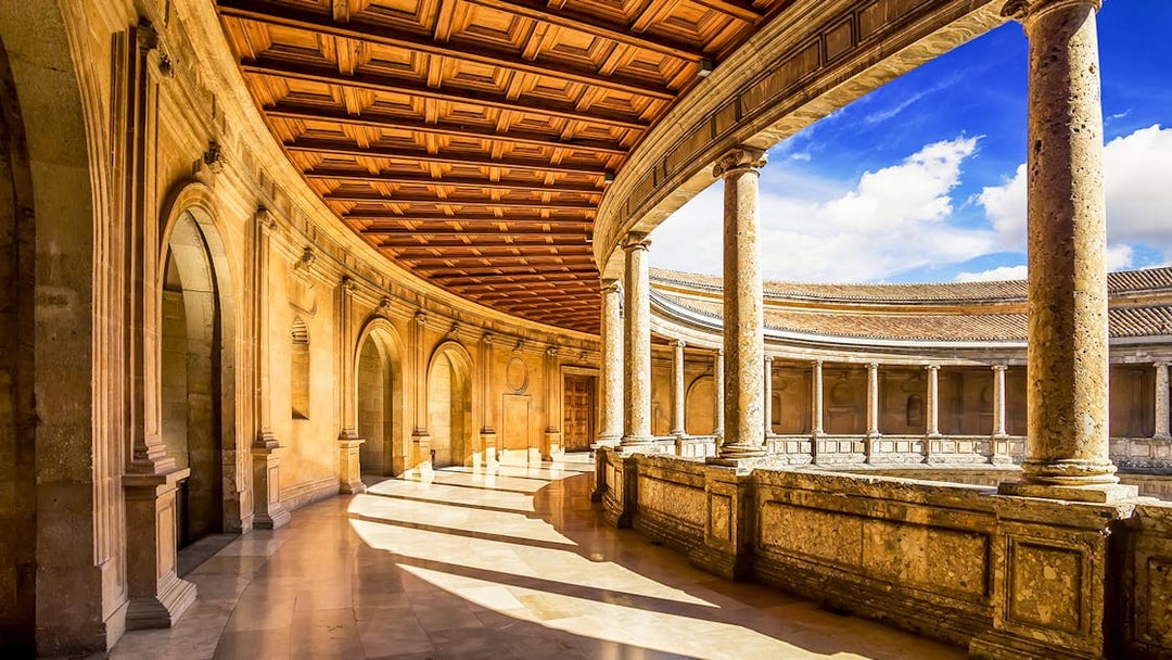 Alhambra's circular courtyard with stone columns and arches, Granada, Spain.