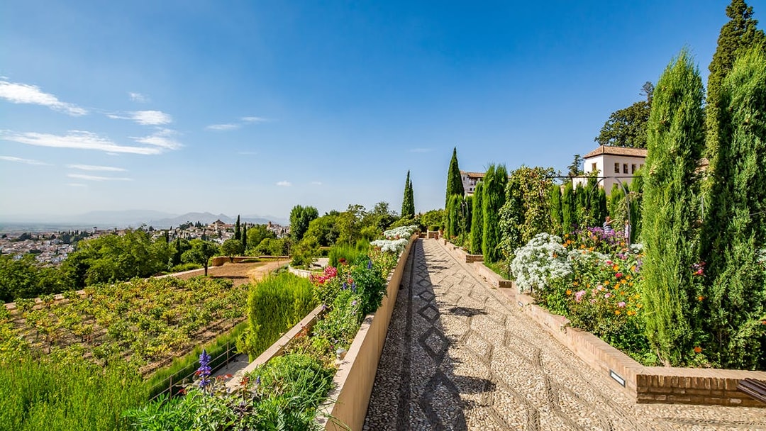 Pathway through gardens at Alhambra with city view, Granada, Spain.