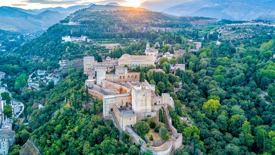 Aerial view of Alhambra and Generalife surrounded by lush greenery in Granada, Spain.