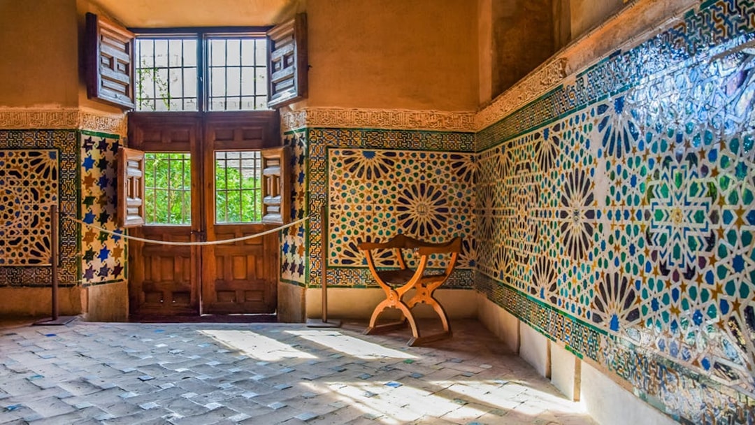 Alhambra interior with intricate mosaic tiles and wooden window, Granada, Spain.