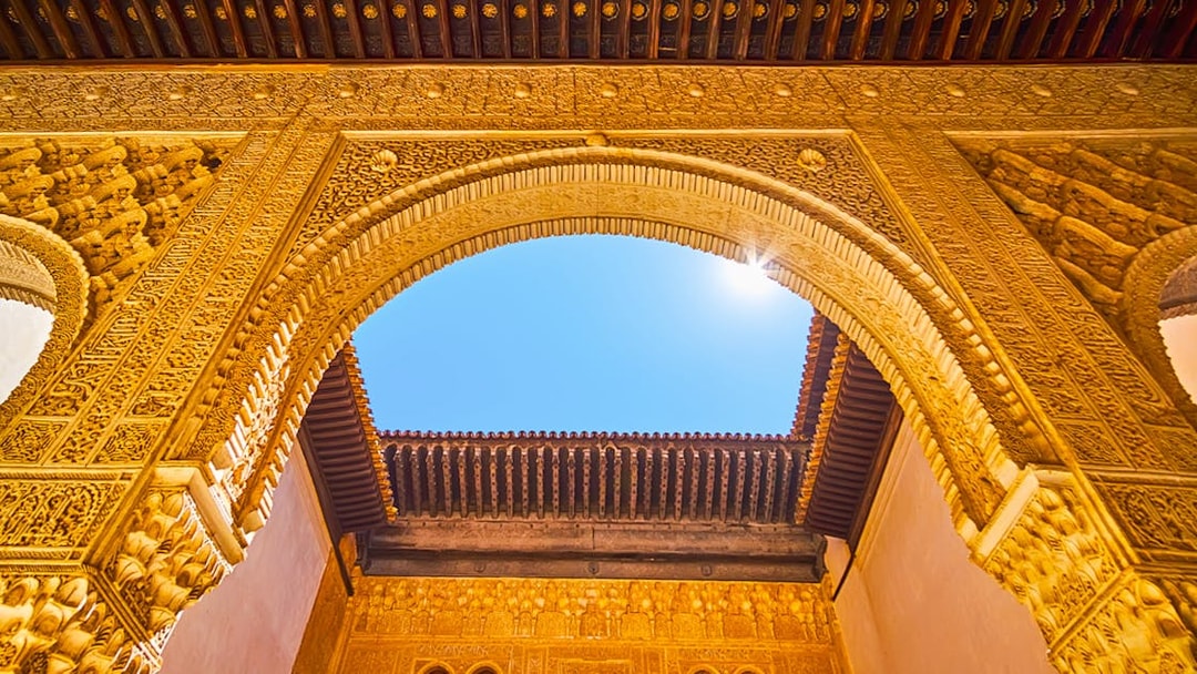 Ornate archway detail in Alhambra, Granada, Spain, under a clear blue sky.
