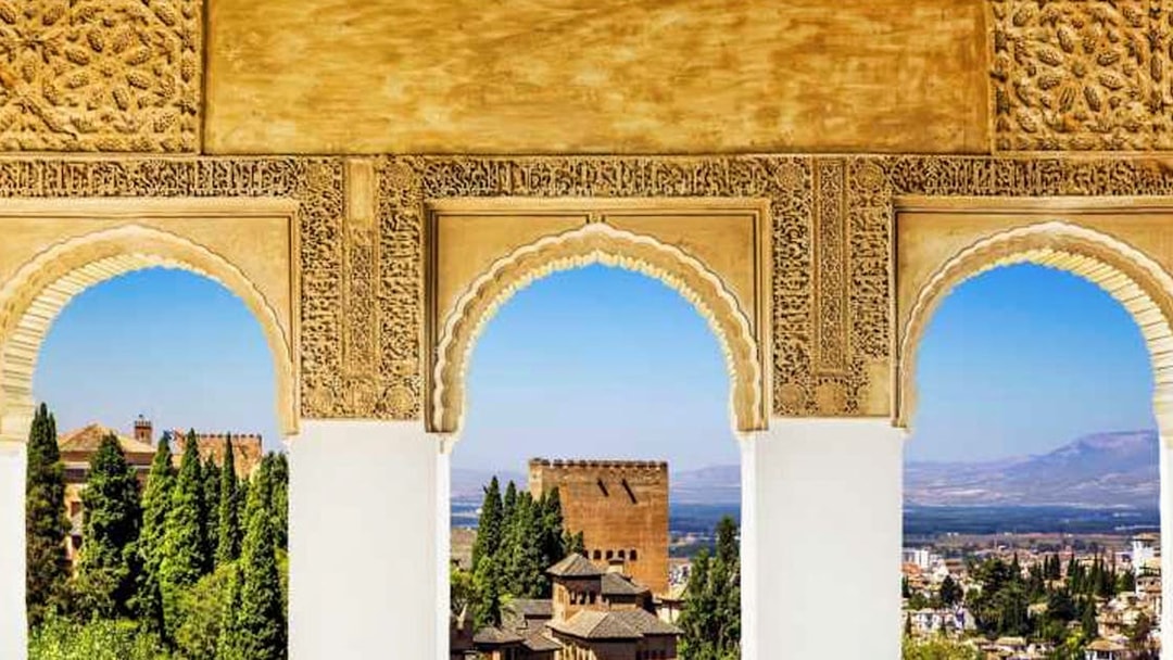 Alhambra arches overlooking Granada cityscape and mountains.