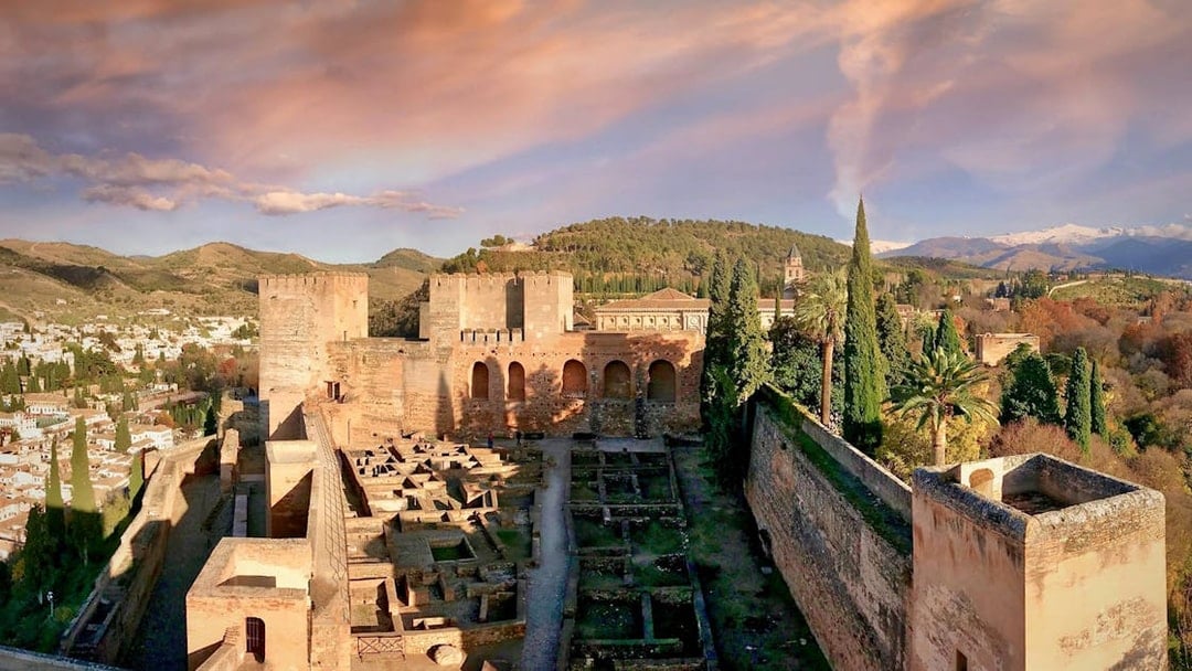 Alhambra fortress with Nasrid Palaces in Granada, Spain, surrounded by lush hills and cityscape.