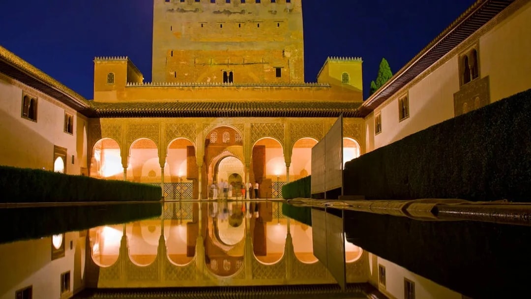 Alhambra's Nasrid Palaces reflecting in a courtyard pool at night, Granada, Spain.