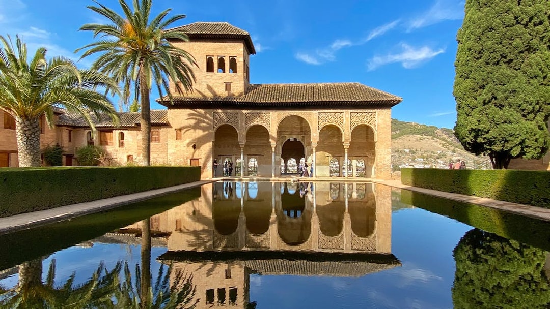 Nasrid Palace reflecting pool with arches and palm trees at Alhambra, Granada.