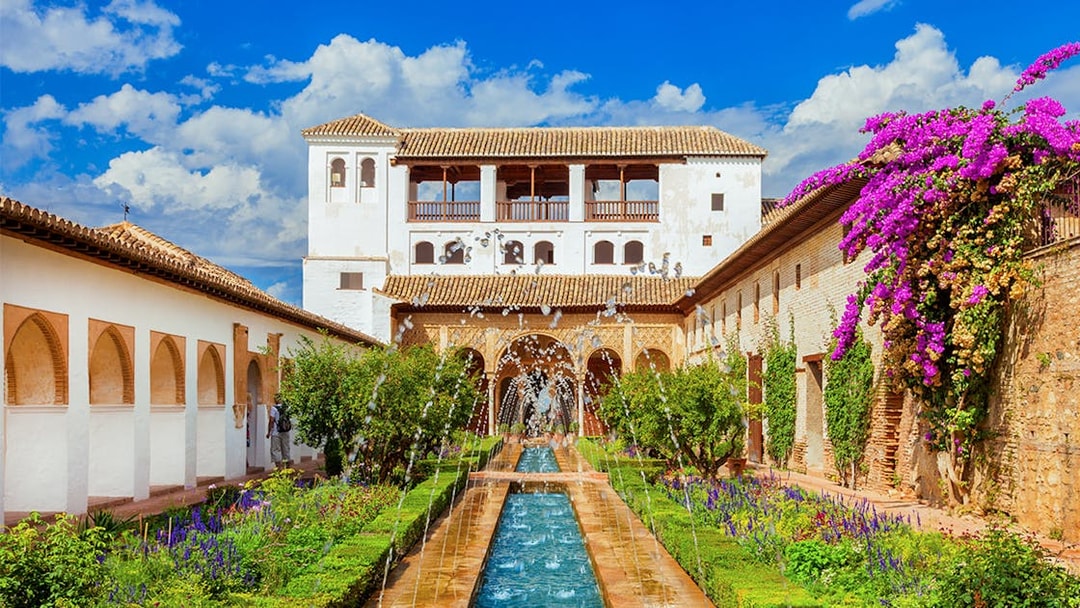 Alhambra's Generalife gardens with fountains and vibrant flowers, Granada, Spain.