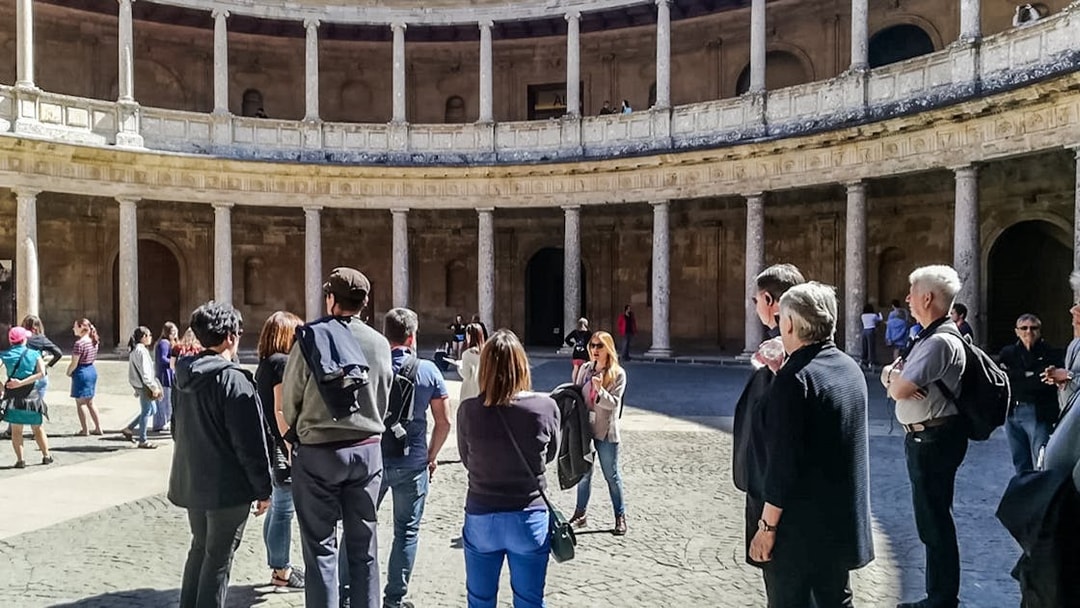 Visitors in the circular courtyard of the Alhambra's Nasrid Palaces during a guided tour.