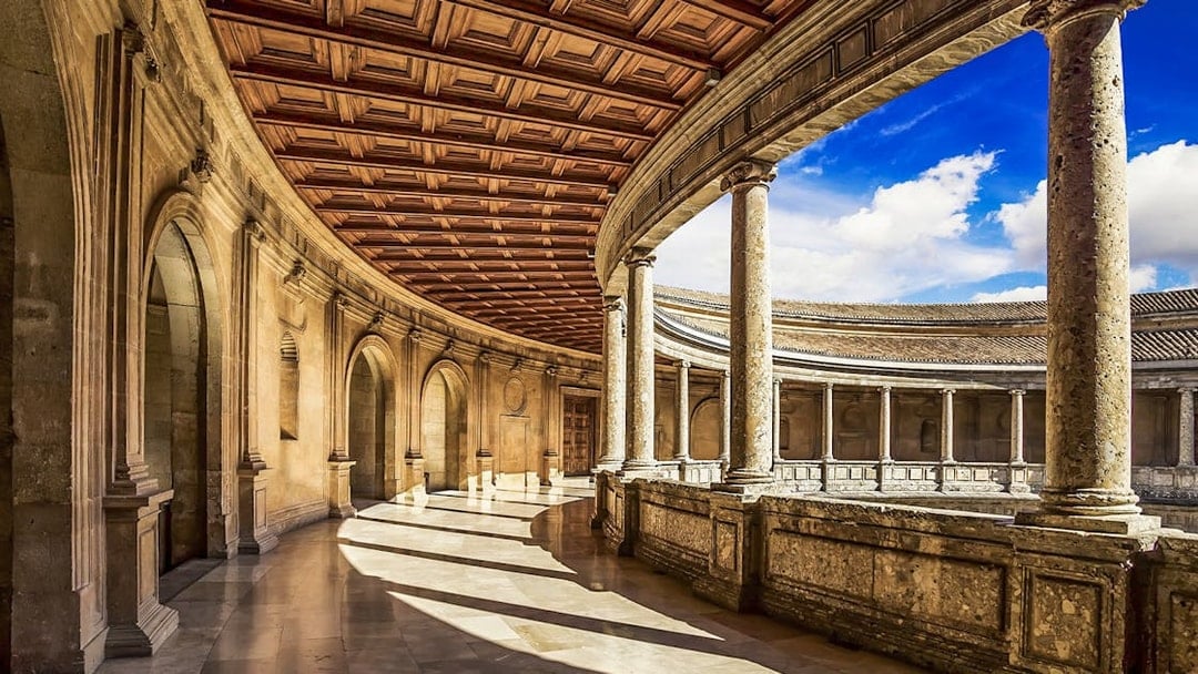 Palace of Charles V interior with stone columns and arches, Alhambra, Spain.