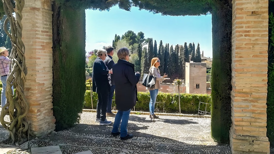 Tour group exploring Alhambra gardens with guide in Granada, Spain.
