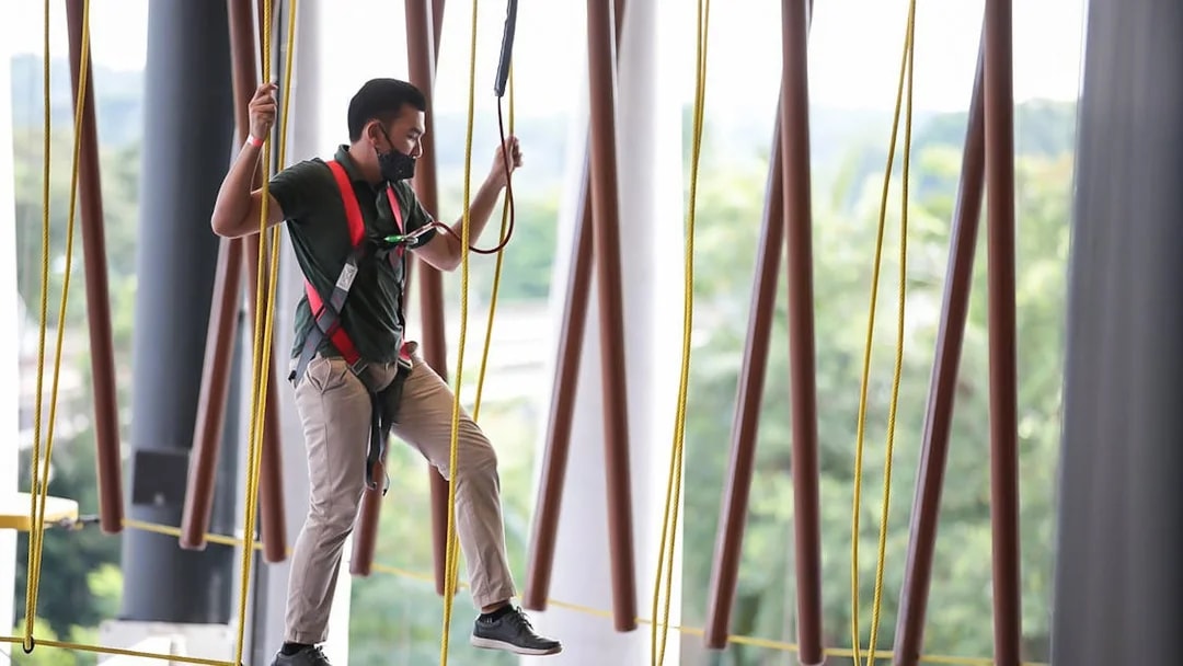 Man navigating ropes course at Adventure HQ with safety harness.