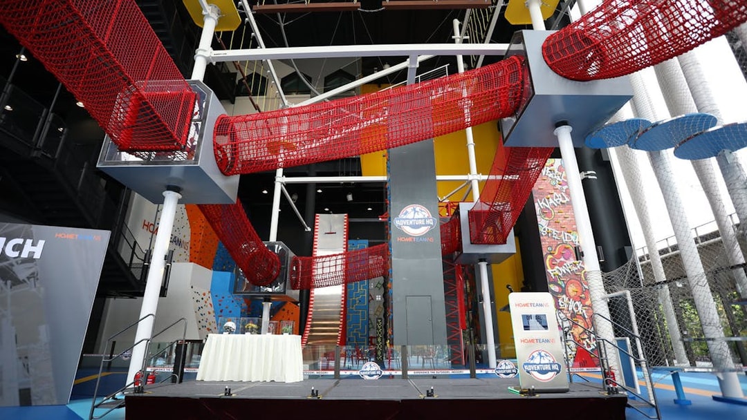 Adventure HQ indoor climbing and obstacle course with red net tunnels.