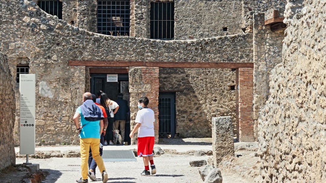 Visitors entering ancient stone building on Pompeii guided tour, Italy.