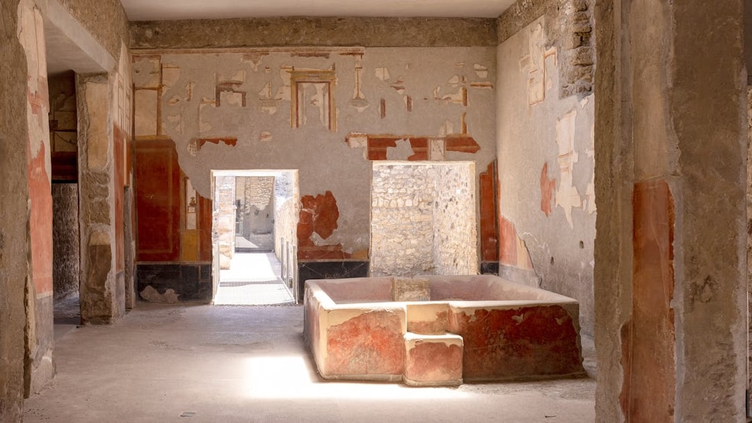 Laundry room with stone bathtub in Stephanus house, Pompeii, featuring ancient frescoes.