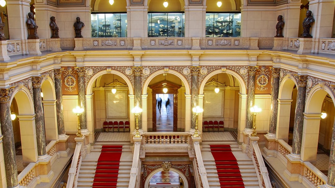 Grand staircase inside the National Museum, Prague, with ornate arches and statues.