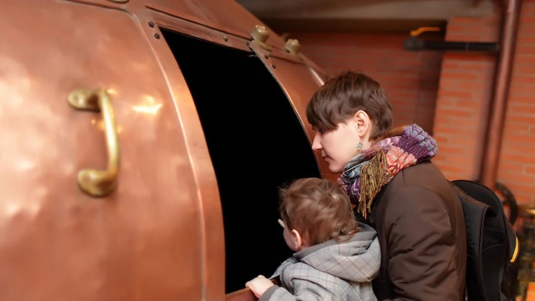 Visitors exploring a copper brewing vat at a Prague museum.