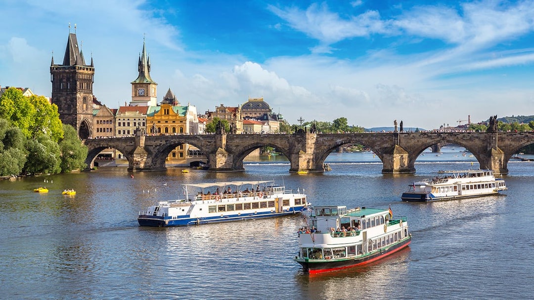 Cruise boats on the Vltava River with Charles Bridge in Prague.