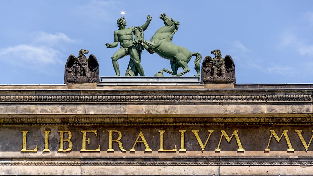 Statue of a man and horse atop Altes Museum in Berlin, Germany.