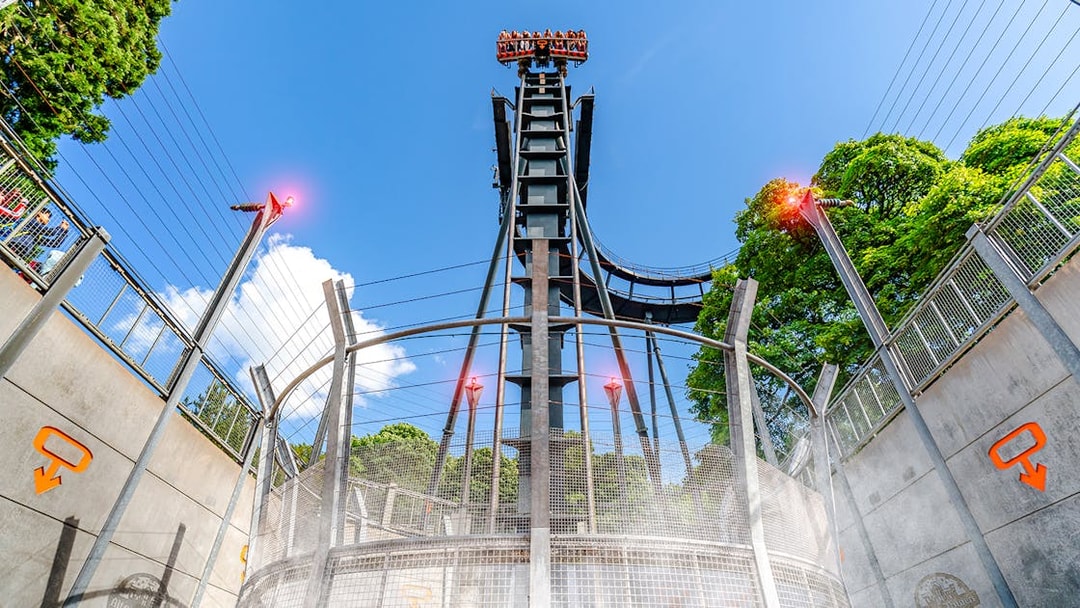 Oblivion ride drop tower at Alton Towers with blue sky and trees in background.
