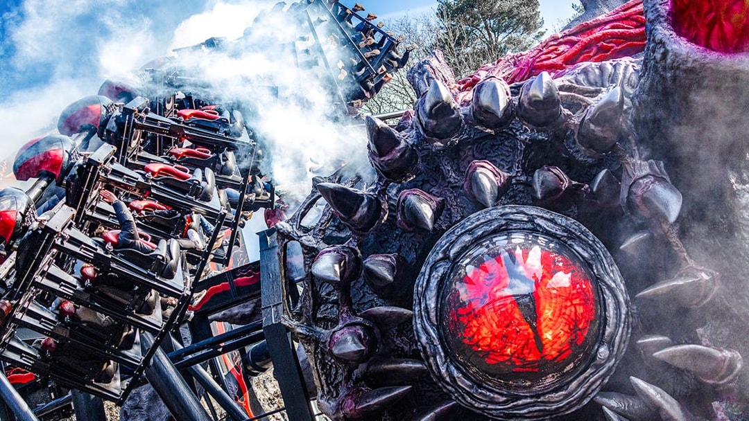 Roller coaster on Nemesis Reborn ride at Alton Towers with dramatic smoke effects.