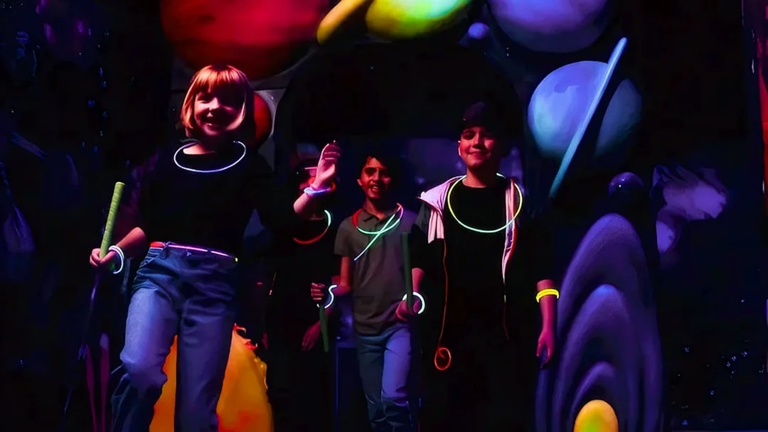 Guests playing Blacklight Mini Golf with glowing accessories and space-themed decor.