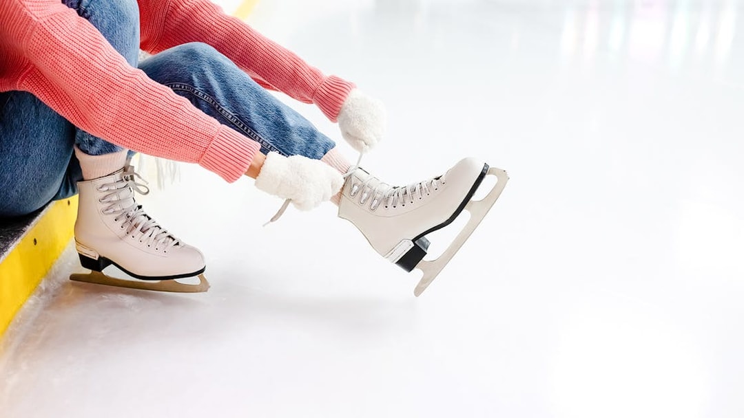 Young woman tying laces on ice skates at an ice rink.