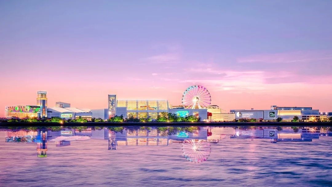 New York City sunset view with Ferris wheel and waterfront reflections.