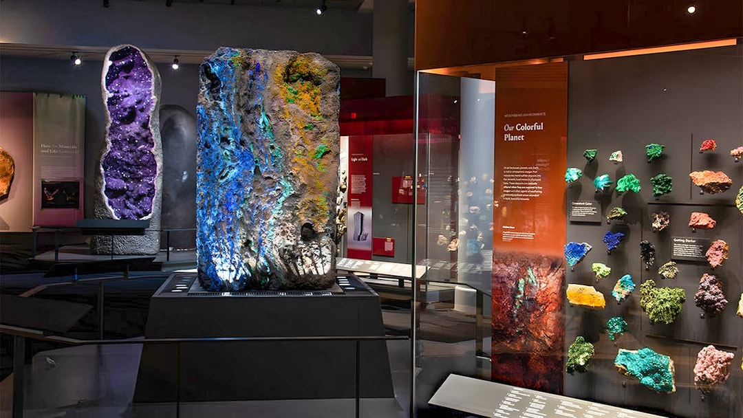 Colorful mineral exhibit at a museum, featuring large geodes and vibrant rock samples.