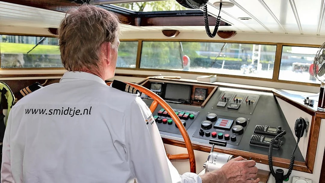 Captain steering a boat on an Amsterdam canal cruise.