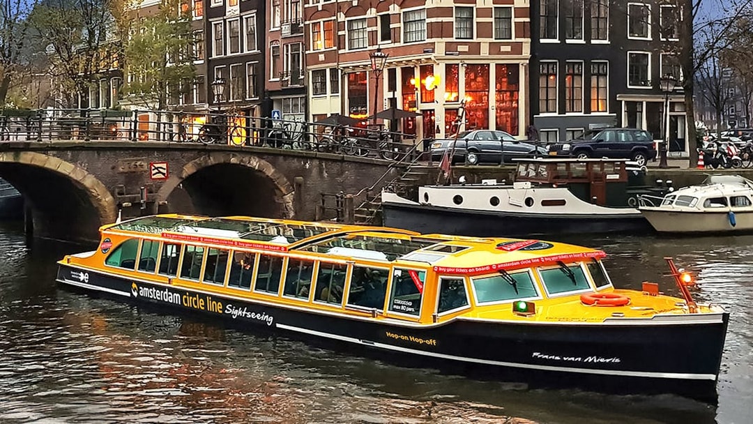 Canal cruise boat on Amsterdam canal with historic buildings in the background.
