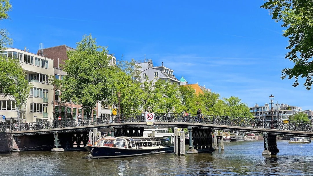 Canal boat passing under a bridge in Amsterdam.