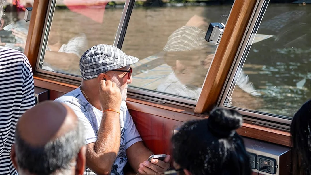 Passengers enjoying Amsterdam canal cruise through boat window.