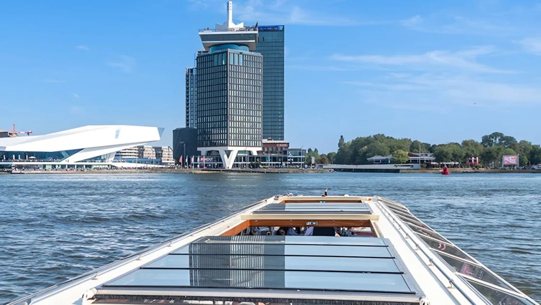 Canal boat cruising past A'DAM Tower and Eye Film Museum in Amsterdam.