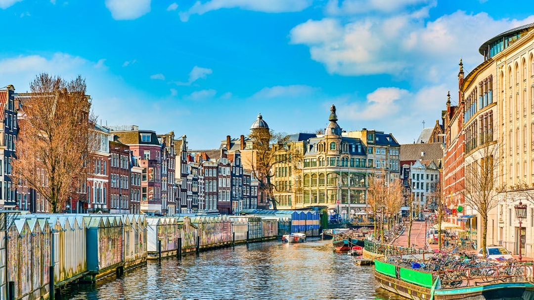 Amsterdam canal with historic buildings and houseboats in early spring.