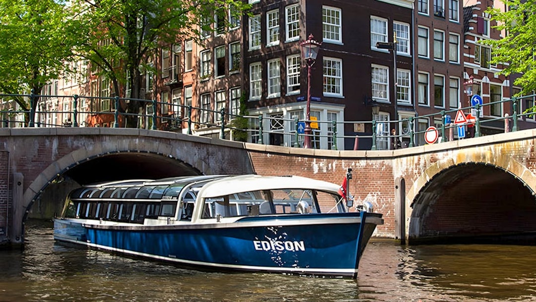 Canal boat cruising under a bridge in Amsterdam.