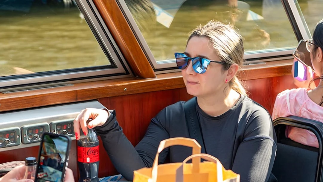 Person enjoying a drink on an Amsterdam canal cruise boat.