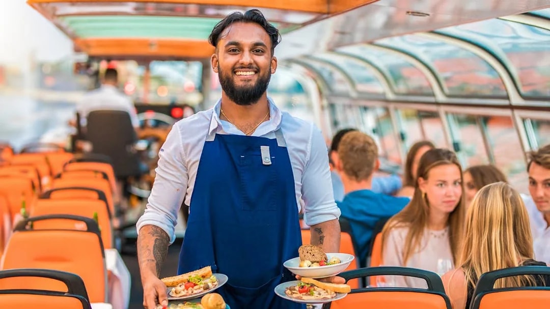 Service staff on a dinner cruise serving meals to guests on a boat.