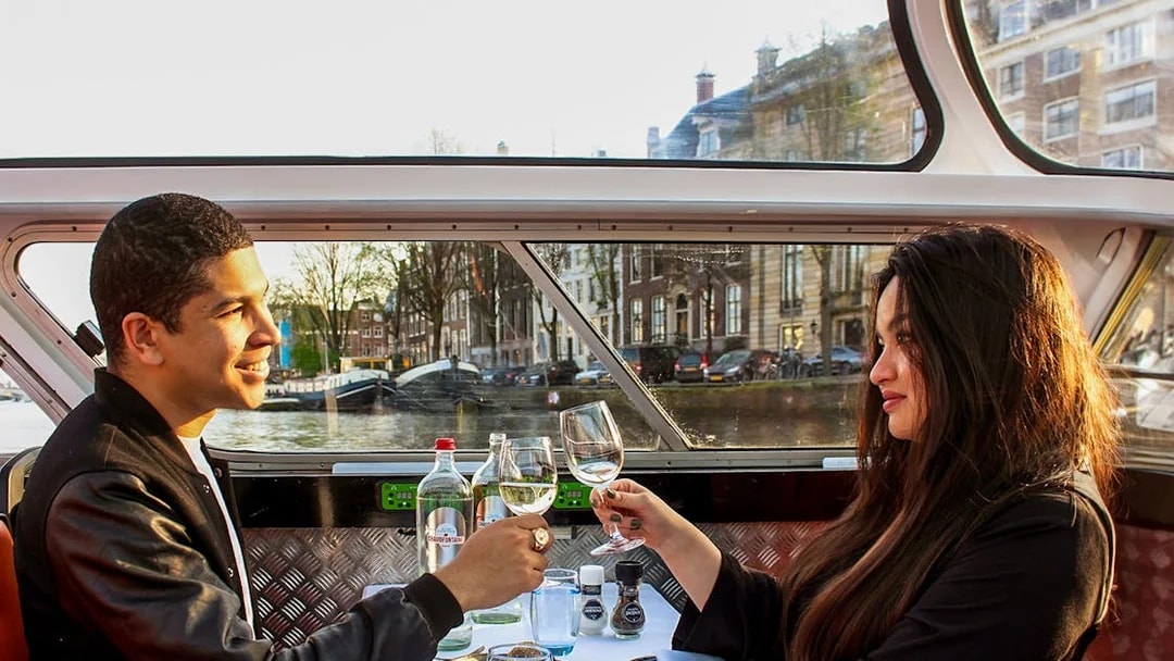 Guests toasting with wine on a canal dinner cruise in Amsterdam.