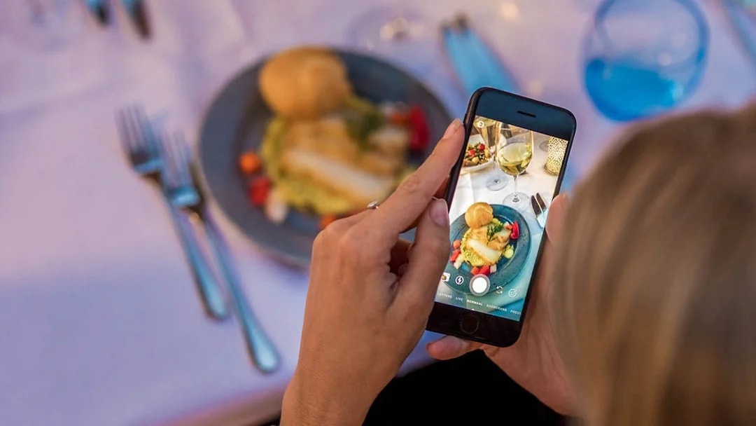 Guest photographing dinner on a cruise with a smartphone.