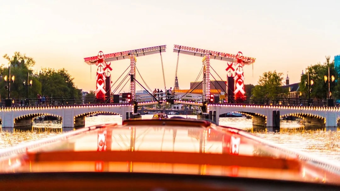 Evening view of the illuminated Magere Brug during a canal cruise in Amsterdam.