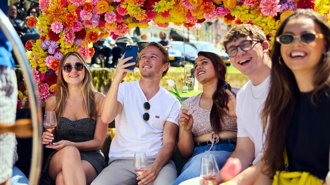 Group enjoying Amsterdam canal cruise on a flower-adorned boat.