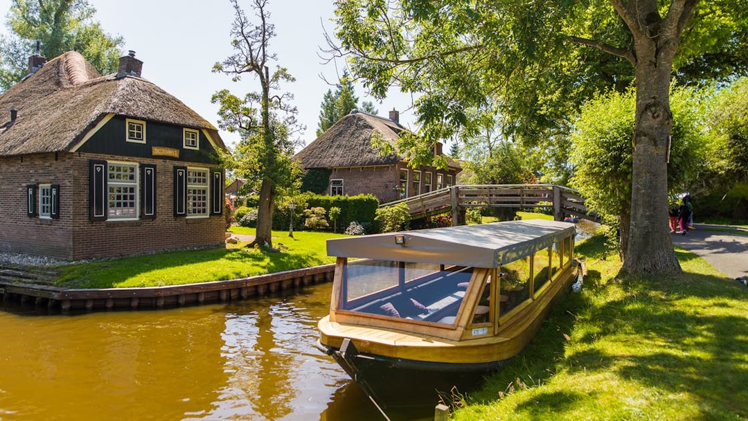 Canal boat near traditional thatched house in Giethoorn, Netherlands, on a day trip from Amsterdam.