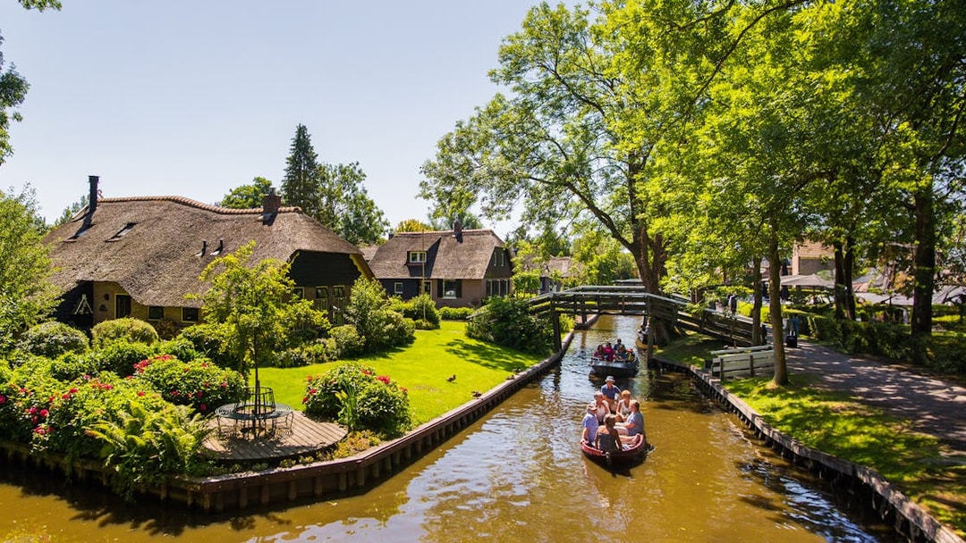 Canal boat tour in Giethoorn with thatched cottages and lush greenery.