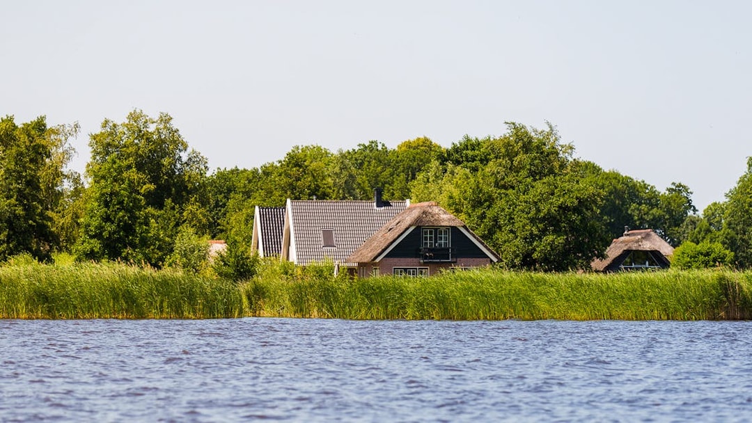 Traditional houses by the water in Giethoorn, surrounded by greenery, seen on a day trip from Amsterdam.