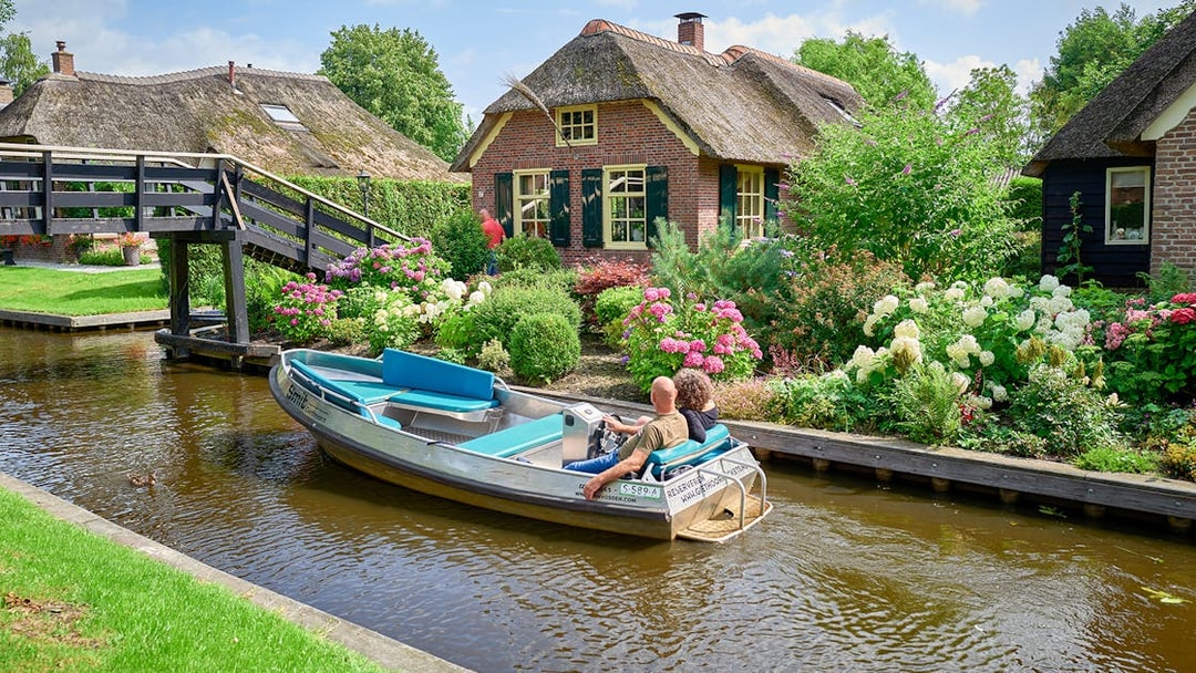 Private boat trip through Giethoorn canal with traditional thatched-roof houses.