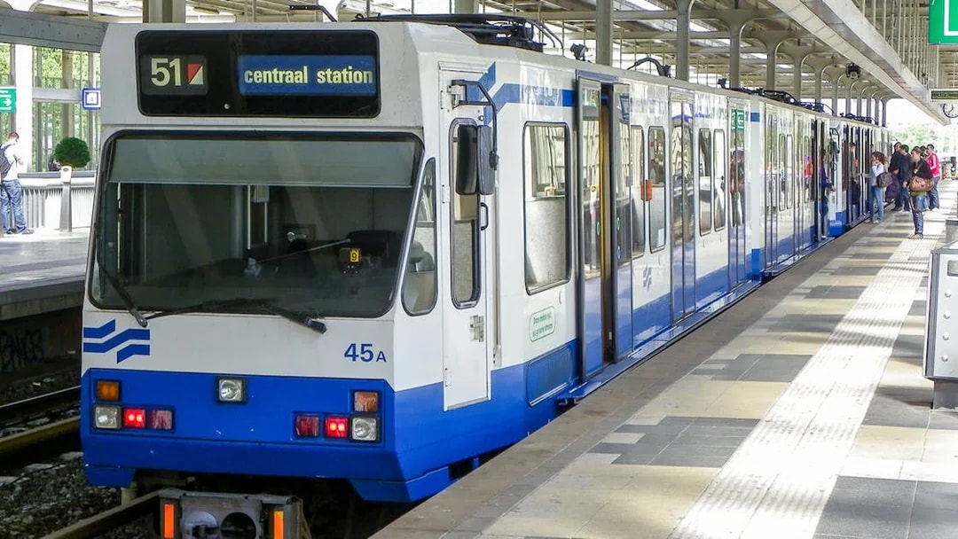 Tram at Amsterdam Centraal Station platform with passengers boarding.