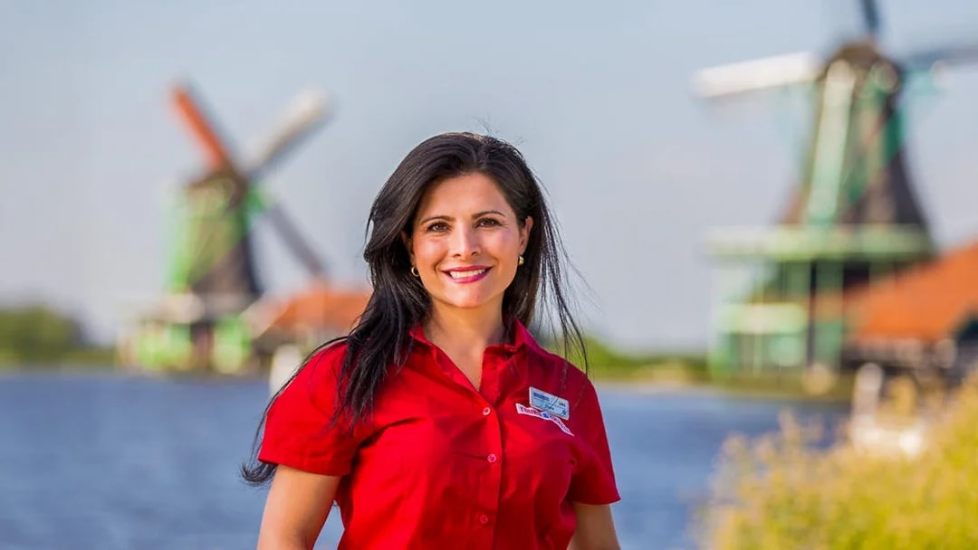 Tour guide at Zaanse Schans with windmills in the background, Netherlands.
