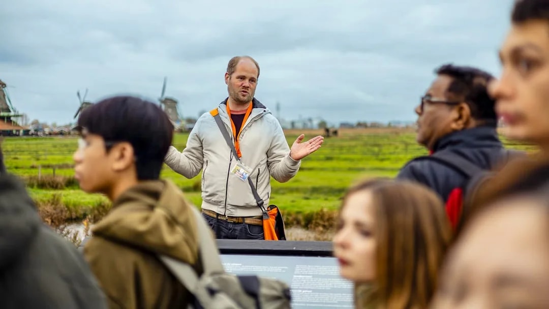 Guide explaining Zaanse Schans windmills to tourists on Keukenhof tour.