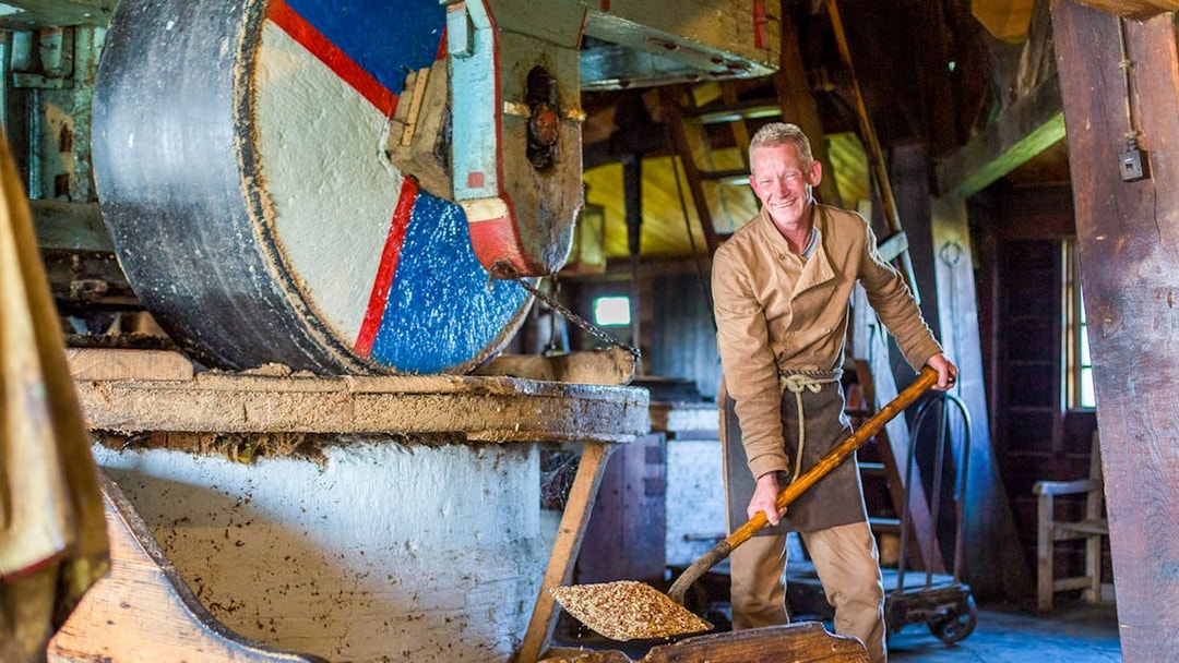Man working in a traditional Dutch windmill at Zaanse Schans during a full-day tour from Amsterdam.