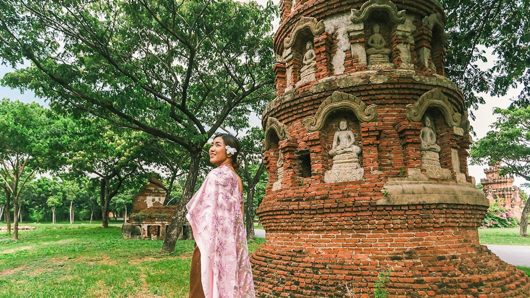 Person in traditional attire near ancient brick stupa with Buddha statues, Ancient City tour.