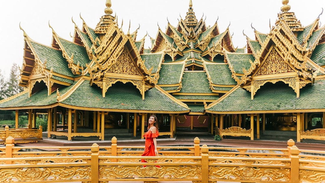 Woman in red dress at ornate pavilion in Ancient City, Bangkok.
